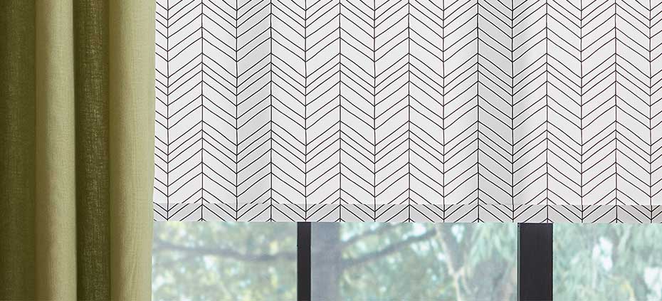 Close up detail shot of patterned roller shade underneat drapery