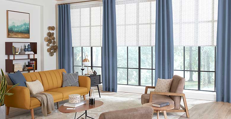 Custom blue drapery panels layered on roller shades in a living room 