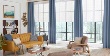 Custom blue drapery panels layered on roller shades in a living room 