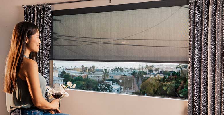 Woman admiring her custom roller shades and drapery panels