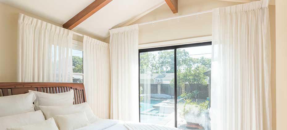 Bedroom with vaulted ceilings and sheer drapery panels